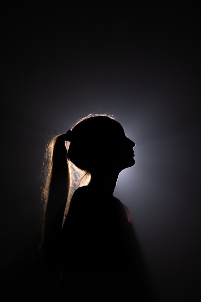 Artistic silhouette of a backlit woman with ponytail, highlighting contours.